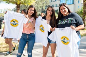 Three alumni holding up their 2022 Homecoming & Family Weekend t-shirts.