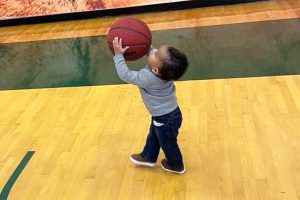 Assistant Coach Ashley Webster's infant son, Aiden, holding a basketball.