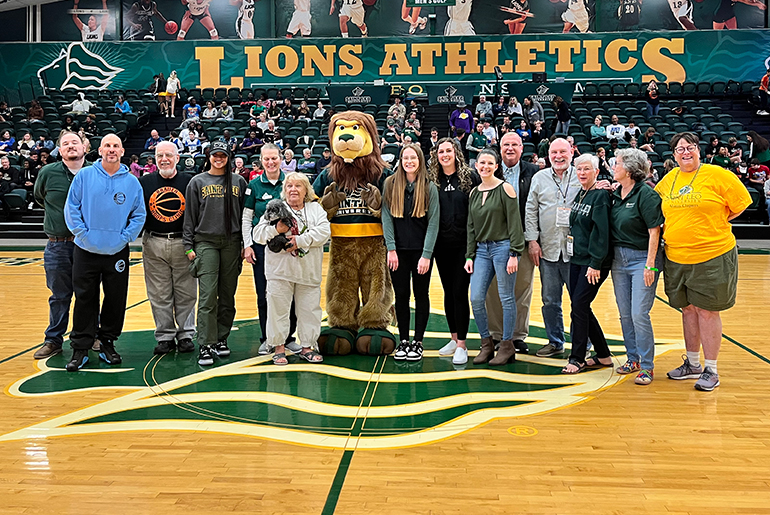 Alumni group and Fritz the lion mascot posing after a Saint Leo basketball game.
