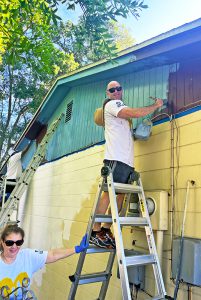 Alumni volunteers painting a house during the Paint Your Heart Out Tampa alumni event.
